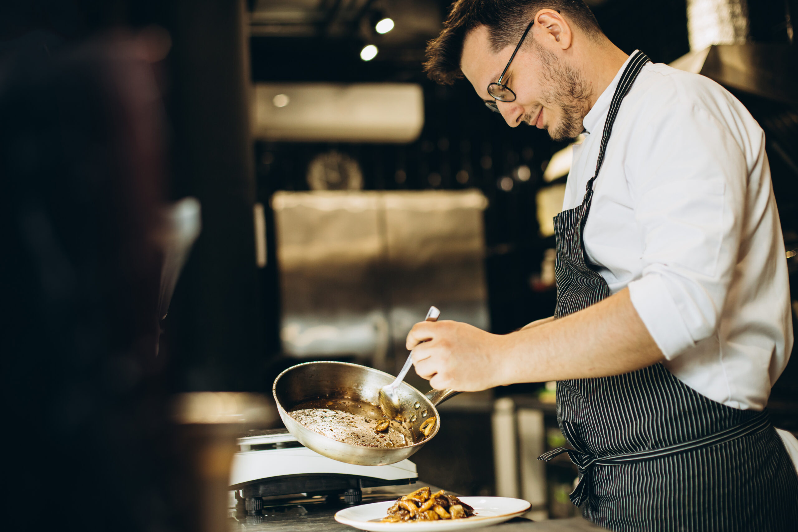 Chef preparing food in a busy cafe kitchen